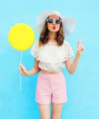 Fashion pretty woman in straw hat with air balloon over blue col