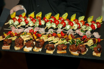 Naklejka na ściany i meble waiter offers flying food appetizer served on black stone plate