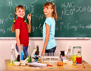 Happy children holding flask in chemistry class. Children written on chemistry blackboard.