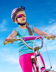 Obraz premium Bikes cycling child. Girl rides bicycle. Little girl in cycling. Cycling is good for child health. Cyclist look away.