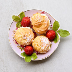 Cream puffs or profiterole filled with whipped cream, powdered sugar topping served with strawberries