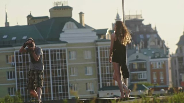 Sport sexy attractive girl model posing on pole on nature for two photographer, slow-motion