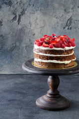 Naked cake with raspberries, strawberries and blueberries on stone table. Natural life