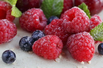 Raspberry, sweet cherry and bilberry on white wooden background.