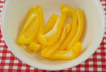 Fototapeta na wymiar Yellow bell pepper slices in white bowl