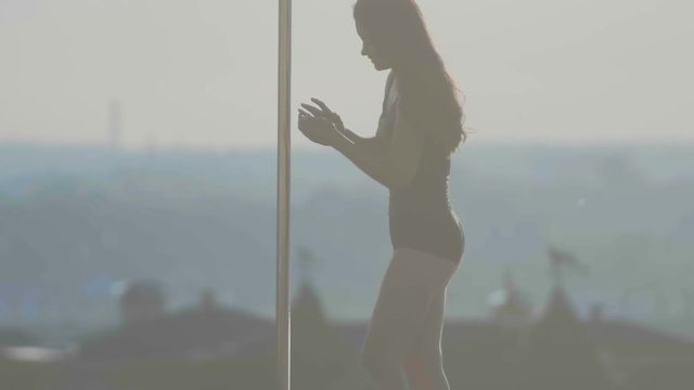 Fit attractive girl poledancer use phone near portable dancing stage over the skyline