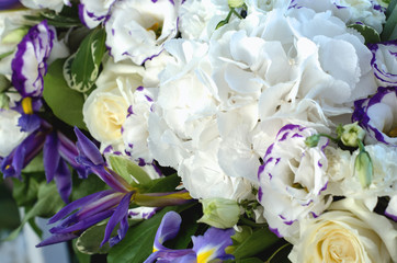 Beautiful fresh floral blue iris, lush leaves, white hydrangea, delicate cream roses with bright background. Summer wedding flowers macro. Copy space, text here