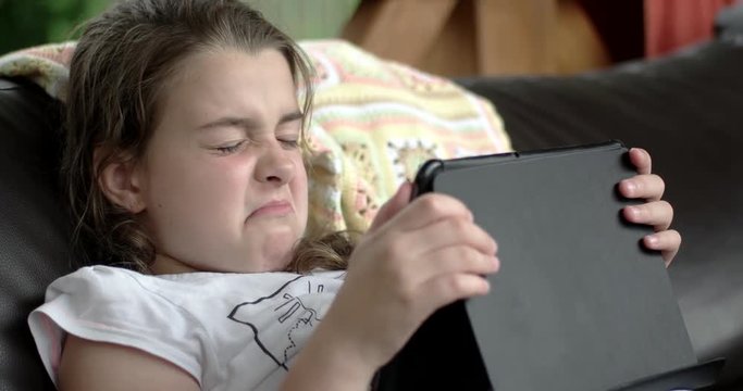 Little Girl Using Tablet Computer on Sofa on Terrace