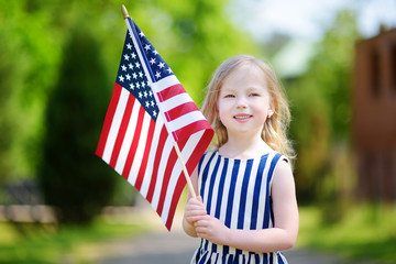 Adorable little girl holding american flag outdoors on beautiful summer day