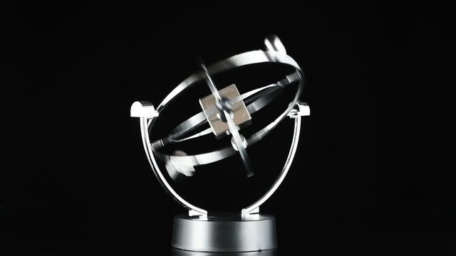 Close up of Newton's Cradle, Desk toy pendulum being activated, black background