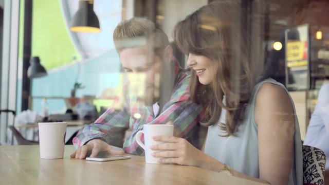 Attractive young couple using smartphone at cafe - Powered by Adobe