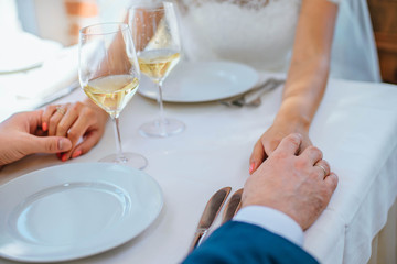 Bride and groom are holding each other's hand in a restaurant