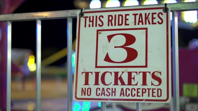 Ride price of 3 tickets posted on fence at carnival.