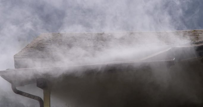 Smoke escaping from around gutter on the eaves of a burning house