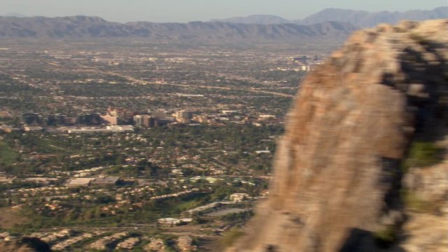 Flight past outlying areas and rocky peak to reveal Phoenix in distance. Shot in 2007.