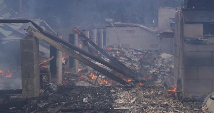 Charred beams lean against cinder block supports amid the ruins of a house destroyed by fire