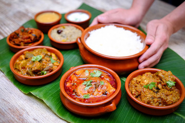 Indian meal with braised pork, curry and plain rice on banana leaf tray