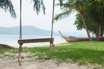 Obraz na płótnie Canvas Rope swing under tree on ocean beach in sunny day