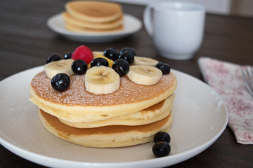 Pancakes with blueberry and bananas on white plate