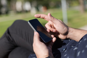 Closeup of smiling handsome bearded man in  shirt using mobile p