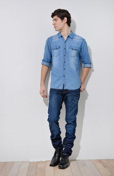 Full Body Young Man In Casual Clothes Posing Over Wooden Background.