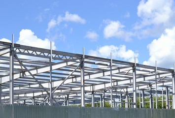 The metal frame of the building.
The frame building under construction against cloudy sky.