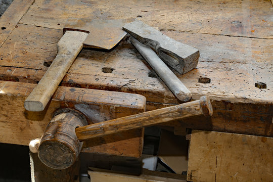 axe and big hammer on the old wooden workbench with a vise