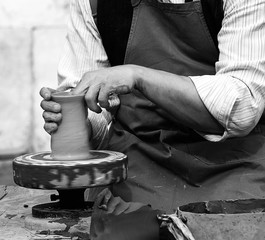Potter with the hand lathe during production of a pot with clay