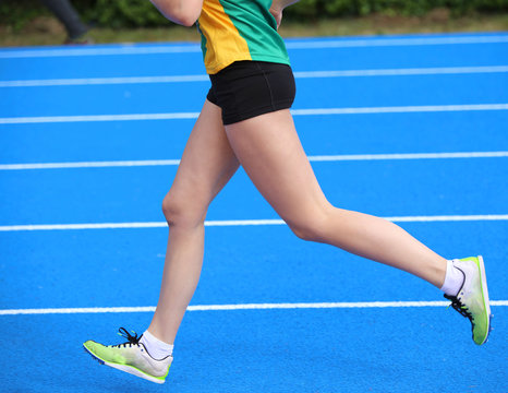 legs of young female athlete runs in athletics track