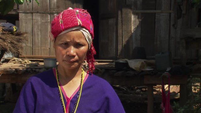 Thai woman wearing traditional costume in front of house raised on poles
