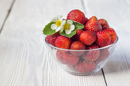 Appetizing strawberry in the bowl. White rustic table