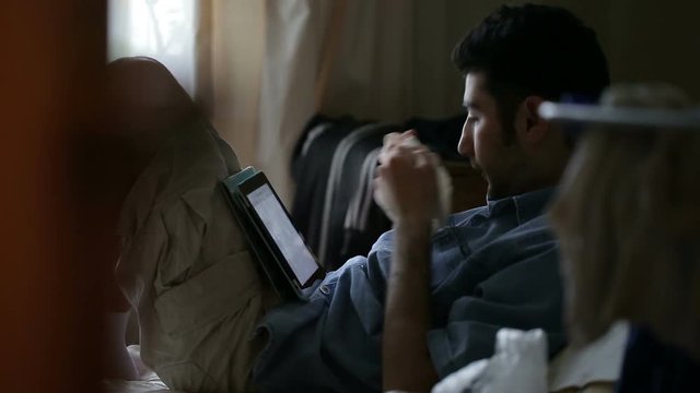 The guy got sick. Young man blowing his nose into a handkerchief and surf the Internet on your tablet