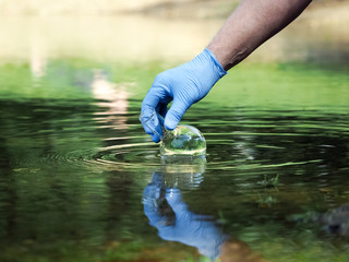 Water sample. Hand in glove collects water to explore. Concept - water purity analysis, environment, ecology. Water testing for infections, permission to swim 