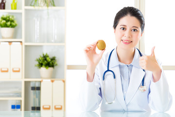 Young asian nutritionist recommend eating kiwi and thumbs up