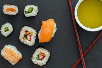 Sushi Set sashimi and sushi rolls served on stone slate