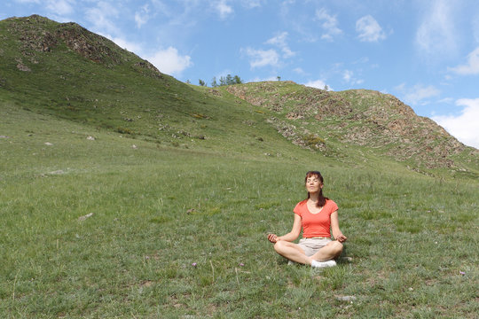 The woman with long hair sitting in a lotus pose among mountains