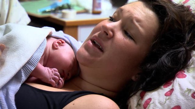 The faces of a young mother and her newly-delivered baby boy