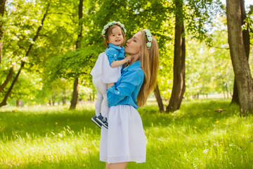 young mother and daughter on a summer walk in the woods in identical dresses