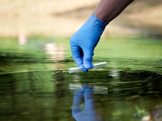 Water sample. Hand in glove collects water in a test tube. Concept - water purity analysis,...