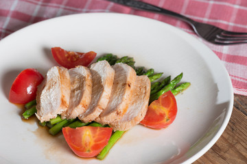 Chicken breast slice with asparagus and tomato..