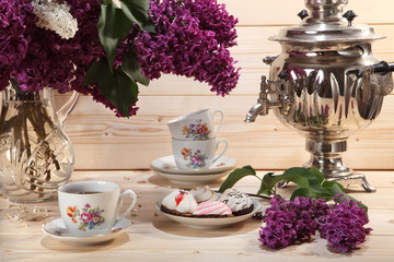 Bouquet of lilacs, samovar, cup of tea and biscuit