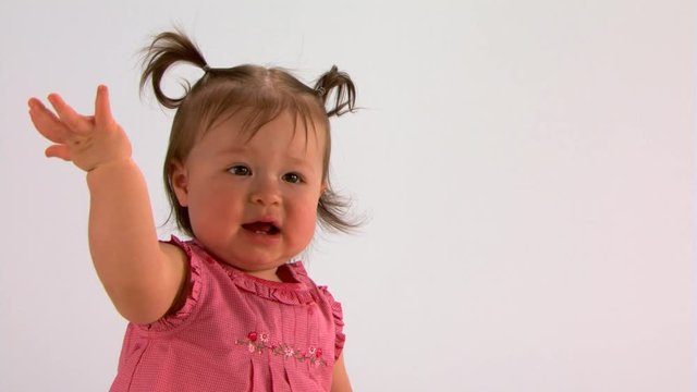 Baby girl in pink dress waving bye-bye