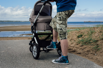 Young man with baby stroller on beach