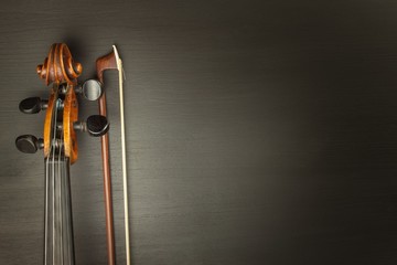 Old violin on dark wooden table. Detail of old violin on a black background. Invitation to the Violin Concerto.
