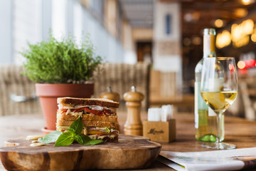 big appetizing sandwich with sauce on the wooden plate in the restaurant