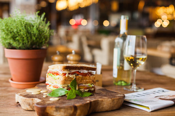big appetizing sandwich with sauce on the wooden plate in the restaurant