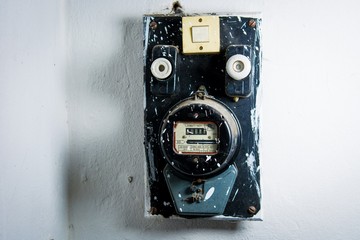 Old dusty electric meter on white wall