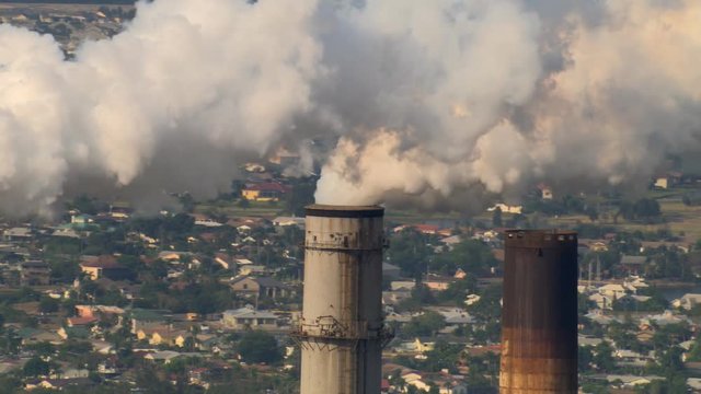 Close-up aerial view of industrial smokestacks emitting smoke