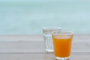 Orange juice on wood table with beach background