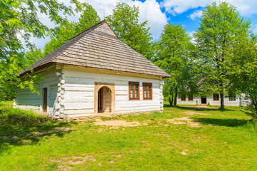 An old rustic cottage house on green meadow in open air museum in Tokarnia village, Poland